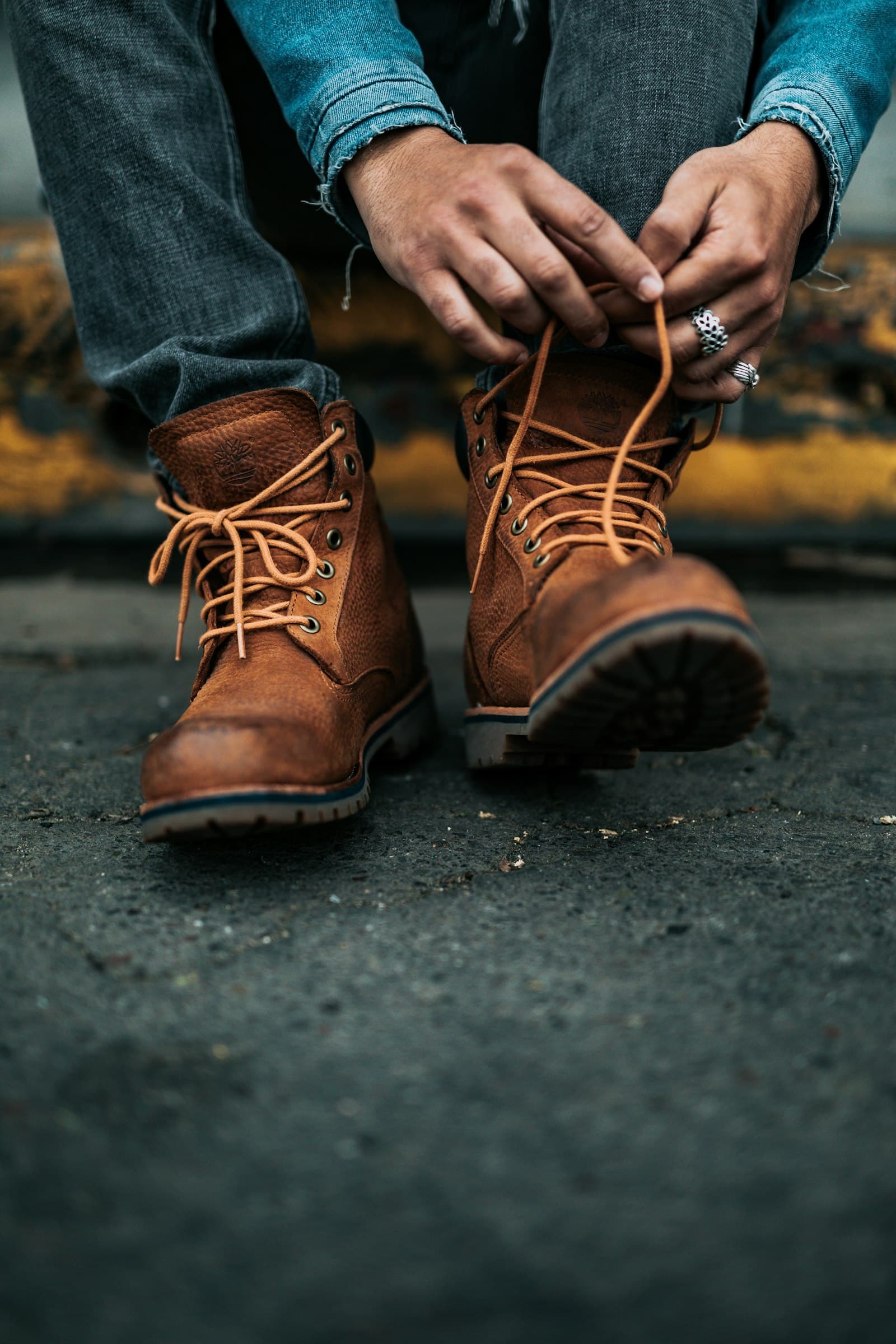 A person lacing up a pair of brown leather boots