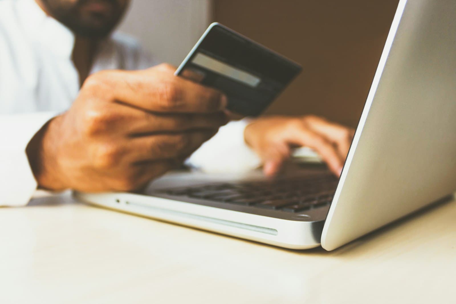 A person holding a credit card while typing on a laptop